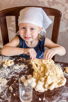 pretty little girl having fun kneads dough