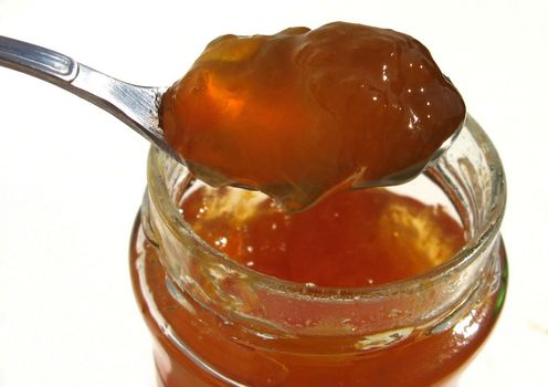 spoon scooping honey from jar on white background