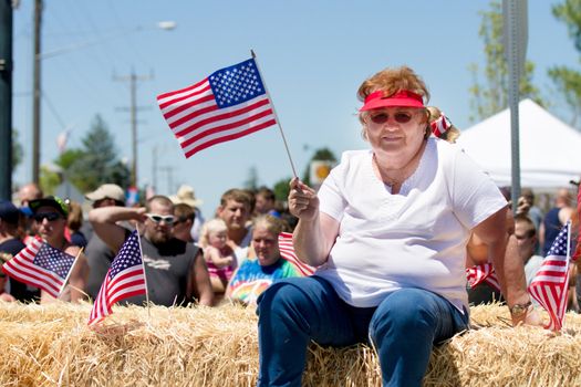 Middleton, Idaho July 4th 2012 - Unidentified Woman in front of a large crowd sitting on bales of hay celebrating the fourth of july parade.