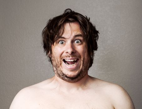 Topless man making a creepy looking smile at the camera against a lightly textured background