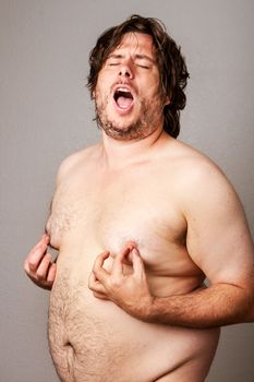 Funny picture of an overweight man pinching his own nipples while standing their nude
