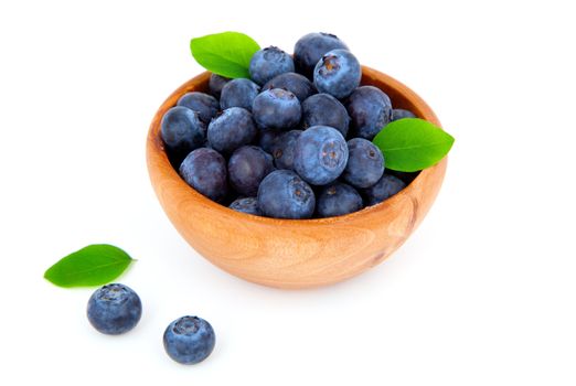 fresh blueberry in a wooden bowl with leaves, over a white background.