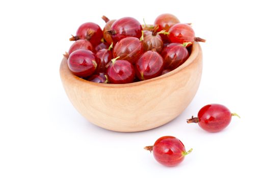 fresh red gooseberries in a wooden bowl, over a white background.