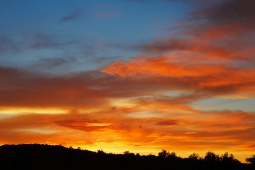 Red, orange, yellow, and blue sunset over prarie ares of Arches national Park