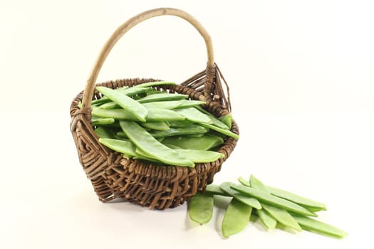 fresh green Sugar peas in a basket on a light background