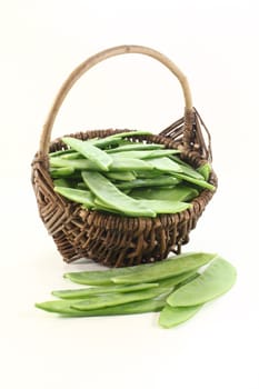 fresh Sugar peas in a basket on a light background