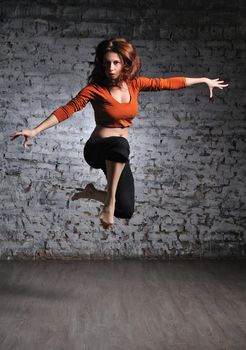 Girl in sportswear jumping on the brick wall background