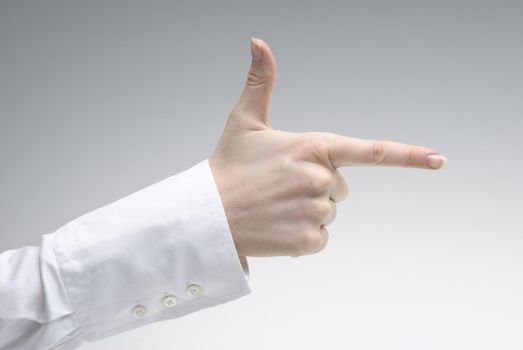 Woman's hand showing pistol symbol  over light background