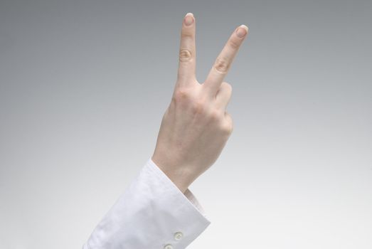 Woman's hand showing Victory symbol over light background