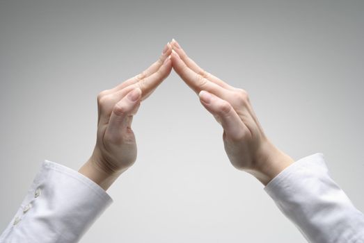 Woman's hand showing roof symbol over light background