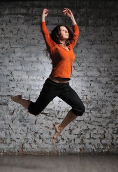 Girl in sportswear jumping on the brick wall background