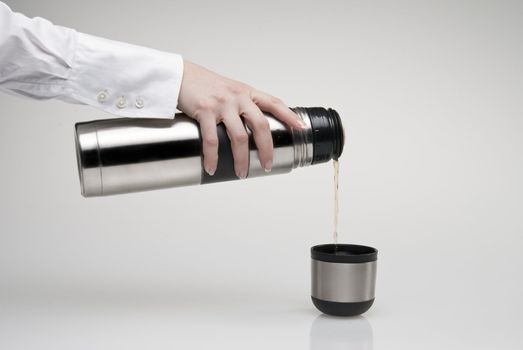 Female hand pouring tea from thermos