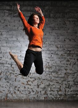 Girl in sportswear jumping on the brick wall background