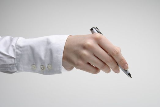 Woman's hand holding silver pen over light background