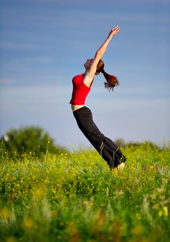 Happy young woman in sport wear jumping on a sunset field