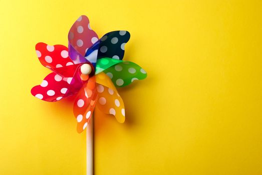 Childrens colorful windmill toy isolated on yellow background