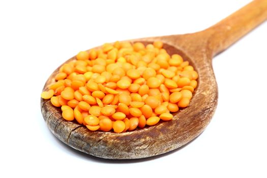 bunch of red lentil in wooden spoon over white