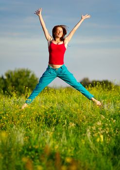 Happy young woman in sport wear jumping on a sunset field