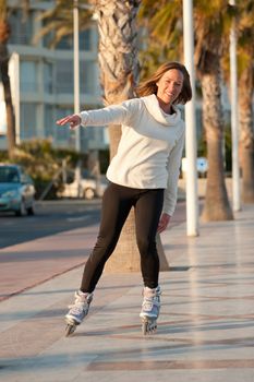 Happy and active woman skating o a sunny promenade