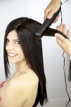 Beautiful smiling female model getting hair straightened