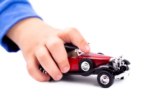 Baby's hand playing with toy car over white background