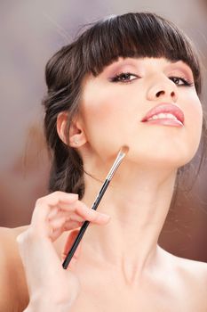 pretty woman applying make up with brush