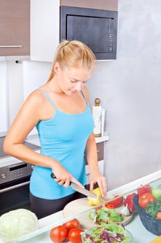 Young woman in kitchen cutting vegetables