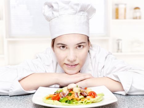 pretty young chef and hers plate of a delicious salad in kitchen