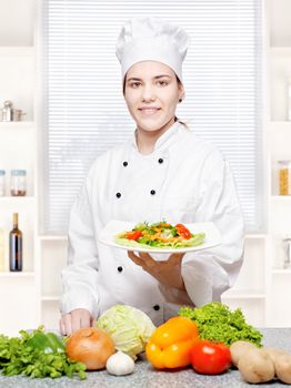 Young chef offering vegetarian meal in kitchen