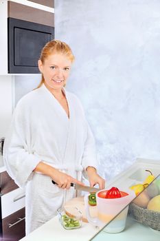pretty woman making fruit salad in kitchen