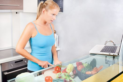 Young woman in kitchen with laptop