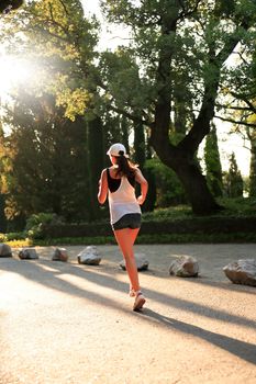 Young beauty woman running across park during sunrise