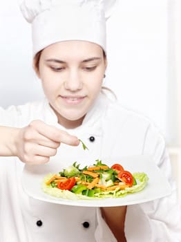 pretty young chef decorating delicious salad