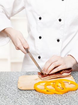 chef cutting bacon on board