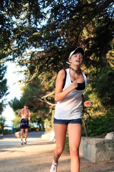 Young beauty woman with smile on her face running across green morning park