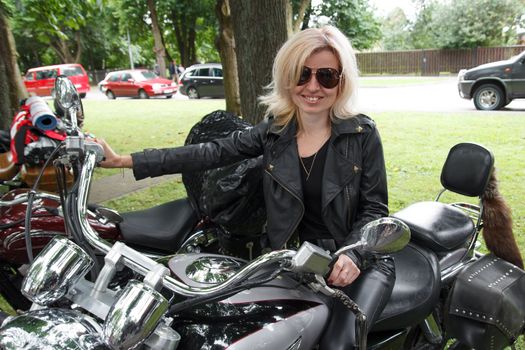 smiling biker girl dressed in leather clothes on a motorcycle