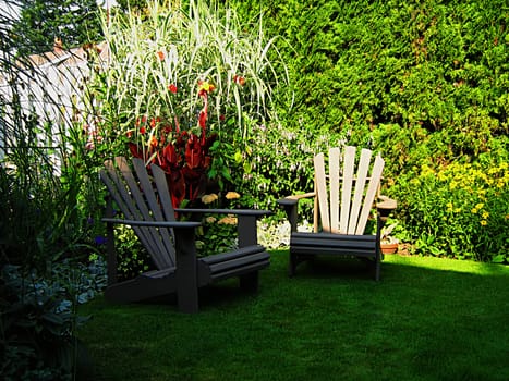 A photograph of a pair of wooden lawn chairs located in a garden.