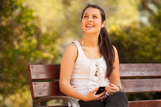 young latin woman using celphone looking up outdoors