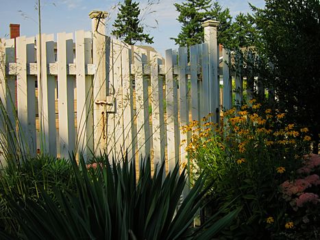 A photograph of a wooden fence located in a flower garden.