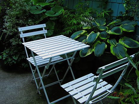 A photograph of a set of table and chairs located in a garden.