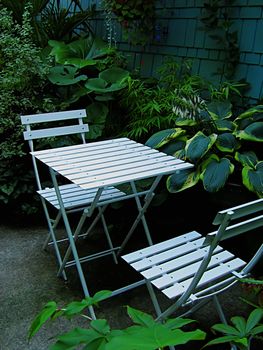 A photograph of a set of table and chairs located in a garden.