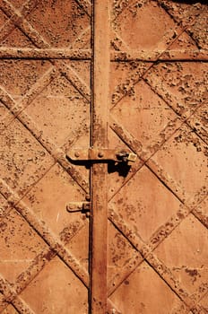 Ancient vintage retro rusty abandoned steel door background locked with small lock.