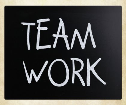 "Teamwork" handwritten with white chalk on a blackboard.