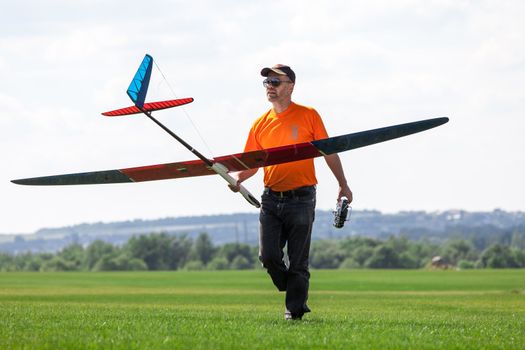 Man holds the RC glider, on grass field