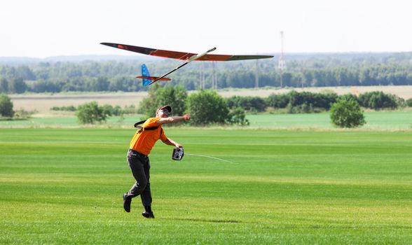 Man launches into the sky RC glider, on grass field