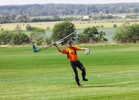 Man launches into the sky RC glider, on grass field