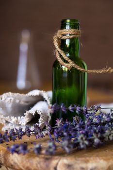 Still life composition with corded small green empty bottle, blue flowers and linen fabric. Shallow DOF