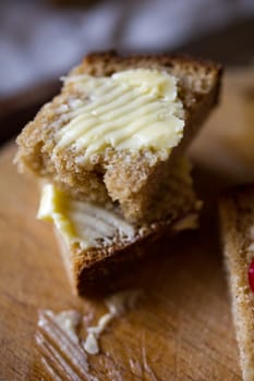 Small sliced piece of wheat bread and butter on the wooden table. Shallow DOF