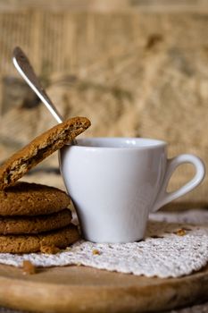 Crumbling oat cookies biscuits with cup of coffee. Shallow DOF