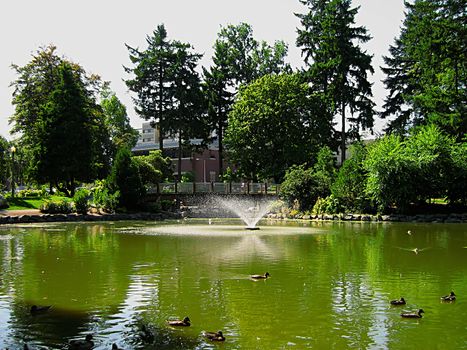 A photograph of a fountain and a bridge located in a public park.